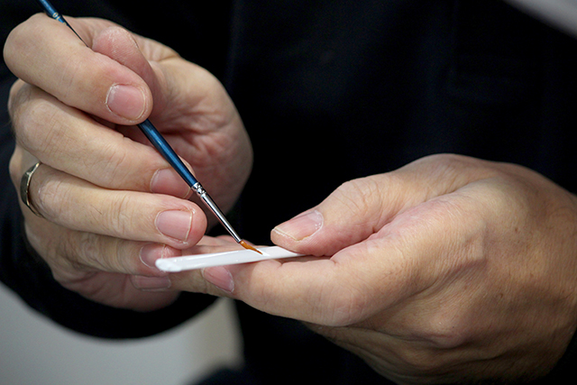 Image of man using a paintbrush to apply glue to part of the ModelSpace Senna McLaren MP4/4 1:8 scale model Formula 1 car, as part of a blog about the top scale model tools and how and when to use them.