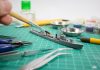 Image of person painting scale model ship, as part of a blog about how to paint model kits.
